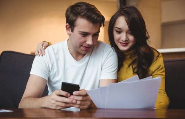 Couple discussing with financial documents and calculator in living room at home
