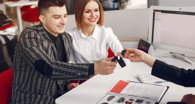 Stylish and elegant people in a car salon People in a car salon. Couple buying the car. Elegant women with handsome man. Manager helps people.